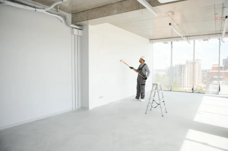 Painter rolling a wall in a large, bright, empty office floor