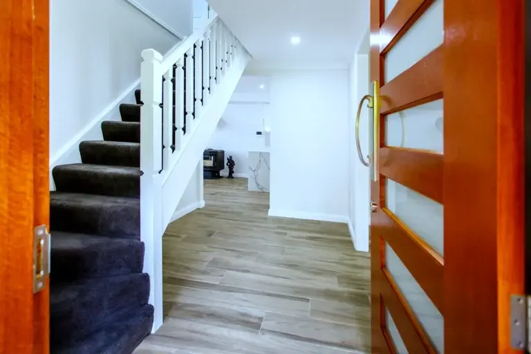 Entry hall with a white staircase balustrade beside a timber front door