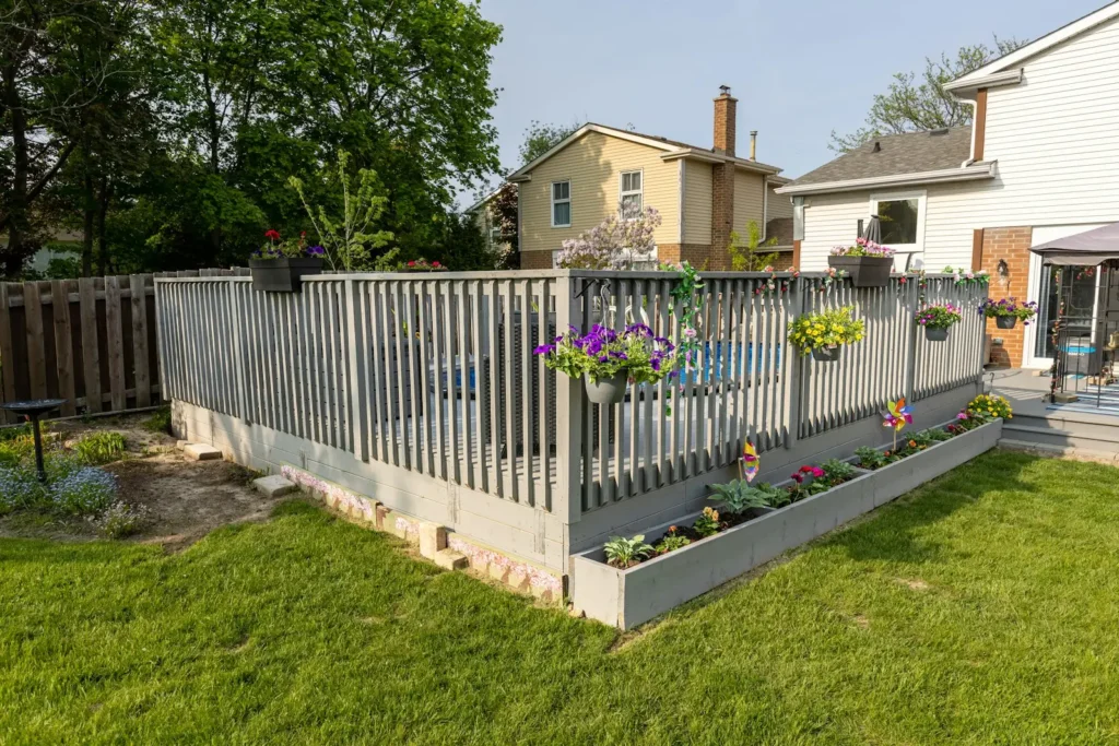 Grey painted timber fence around a backyard deck, with flower boxes and a lawn