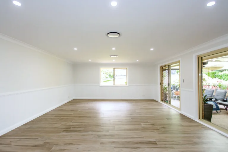 Large living area painted white, with wainscoting and glass doors to the yard