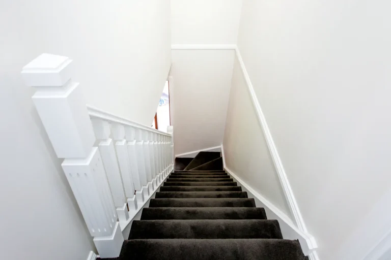 Staircase with a white balustrade between white walls